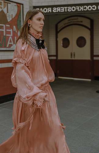 apparel woman wearing pink long-sleeved dress across white door fashion