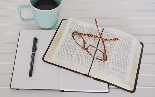 bible flat lay photography of tortoiseshell eyeglasses on top of book near black pen and teal mug glasses