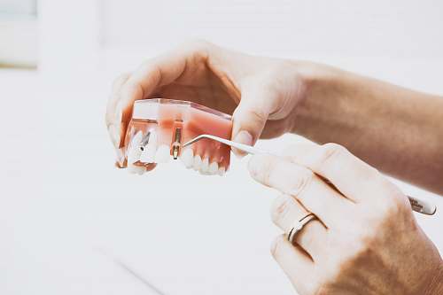 dentist person wearing silver-colored ring while holding denture hand