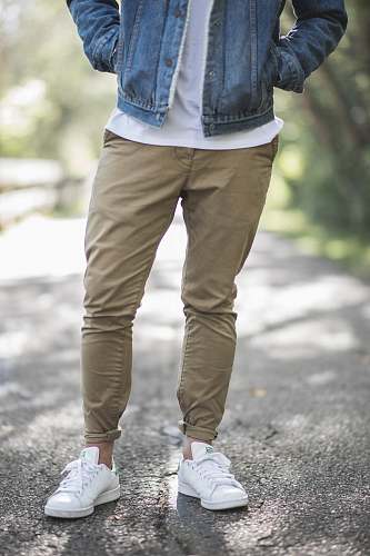 man man wearing brown fitted jeans and sneakers standing on road at daytime male