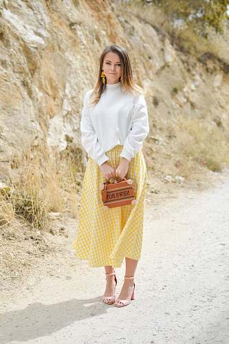 people woman holding brown leather 2-way bag standing near grey rocky mountain human