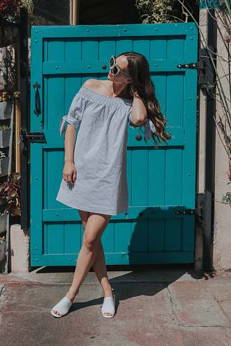 people woman touching her hair standing near teal gate girl