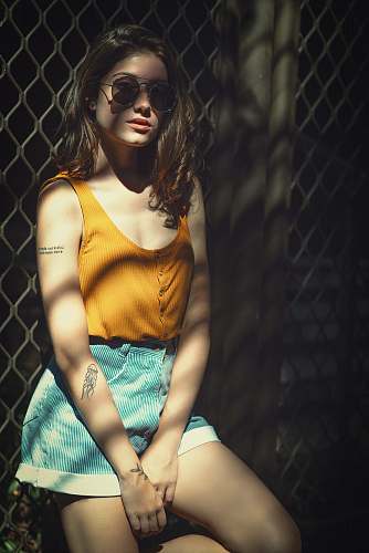 clothing woman wearing yellow tank top lying on cyclone fence apparel