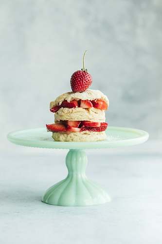 fruit cake with strawberries on teal ceramic cake stand plant