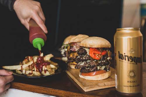 human person pouring ketchup on on potato fries burger
