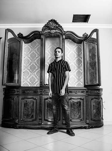 human man standing beside china cabinet black-and-white