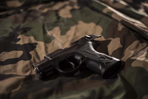 weapon black pistol on green, brown, and black camouflage sheet gun