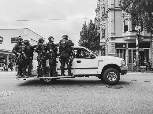 person grayscale photo of men standing beside vehicle black-and-white