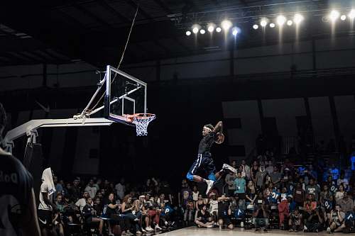 army man jumping and about to shoot the ball in basketball hoop in front of crowd team