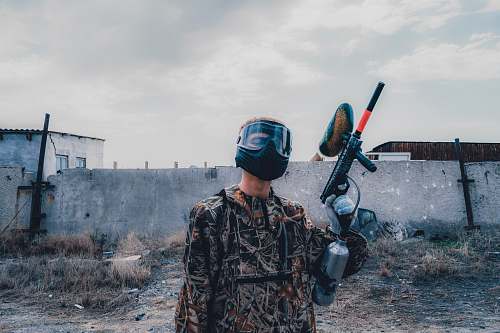 person man wearing mask holding paintball gun during daytime clothing