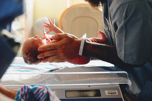person person wearing gray shirt putting baby on scale baby