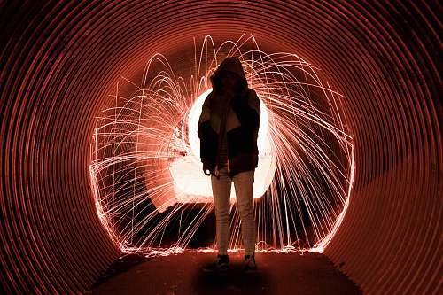 person person wearing hood standing in tunnel lighting