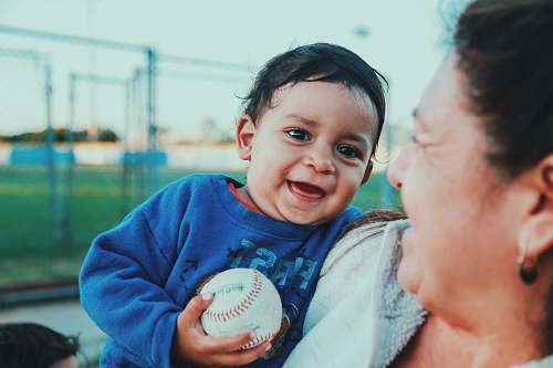 person selective focus photo of baby holding baseball baseball