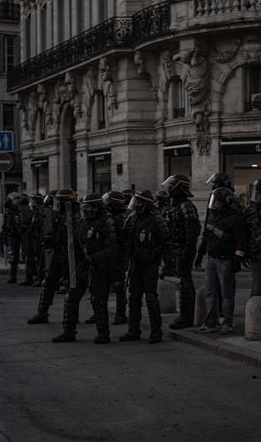 person soldiers holding shields near building black-and-white