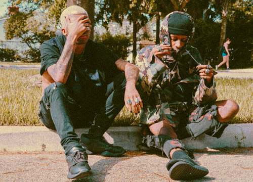 person two men sitting beside road apparel