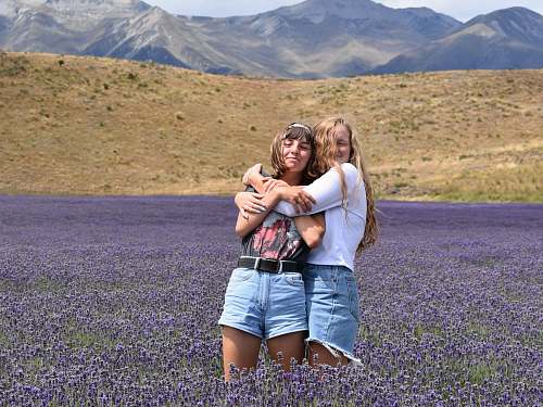person woman hugging another woman on purple flower field people