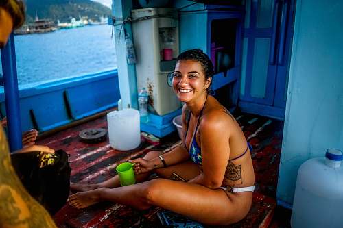 person woman in blue bikini top holding green mug while sitting inside boat people