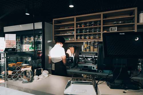 person woman wearing white top behind counter shelf