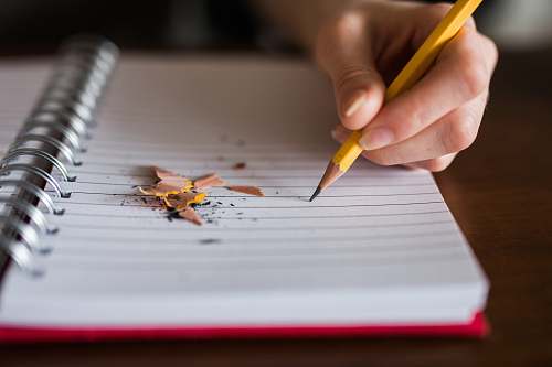 writing person holding pencil writing on notebook notebook