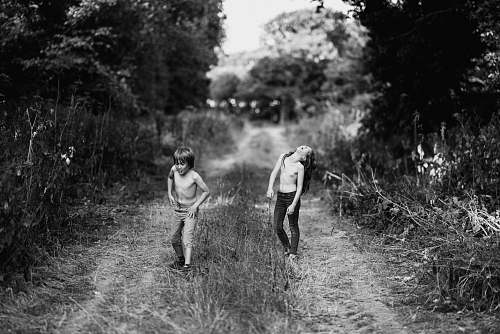 human boy and girl on footpath between grass grayscale photography black-and-white
