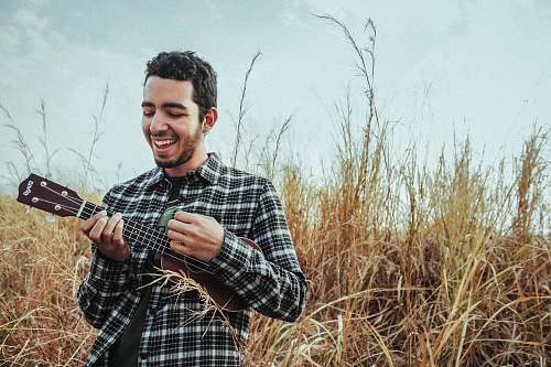 person man playing ukulele while standing on grass field human