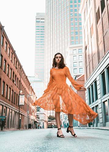 fashion woman in orange long-sleeved dress between buildings during daytime boston