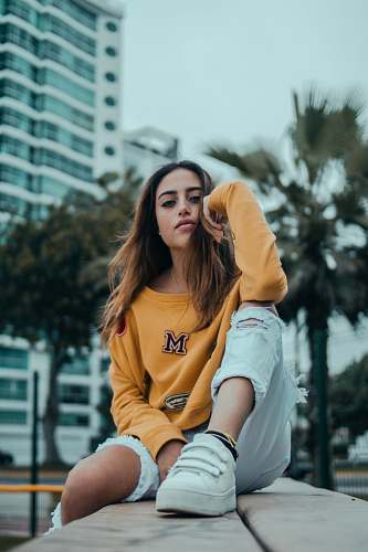 fashion woman sitting on brown surface while being photographed woman