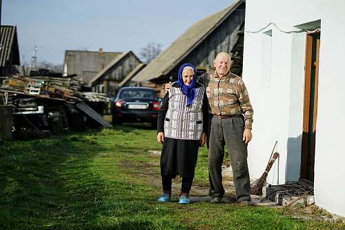 human man and woman standing beside building and near cars automobile