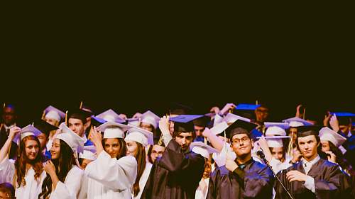 people men and women wearing black and white graduation dress and mortar cap inside building graduation
