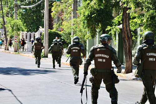 human running and walking men in police uniform holding rifles during daytime apparel