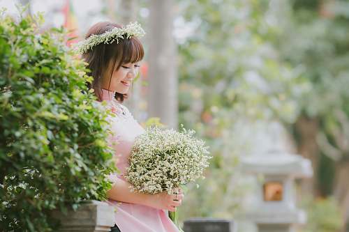 flora selective focus photography of woman holding bouquet of flowers jar