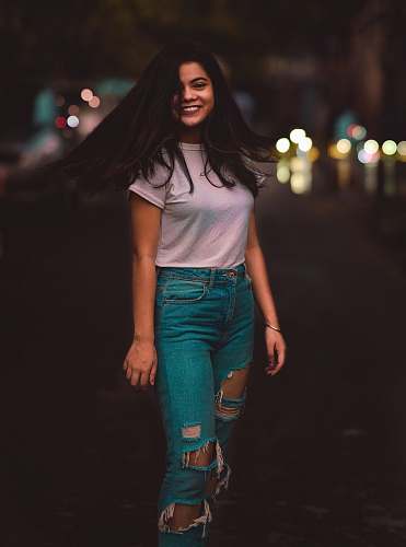 people woman in white crew-neck T-shirt and distressed teal jeans waving hair human