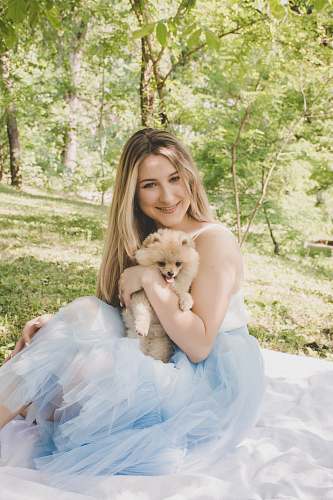 people woman sitting on white picnic mat while holding dog human