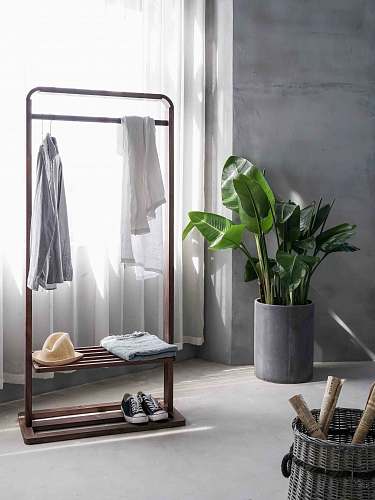 interior gray dress shirt hang on brown wooden rack in front of window with white curtain home