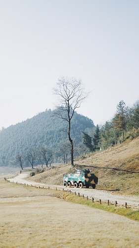 tree green truck parked near bare tree armored