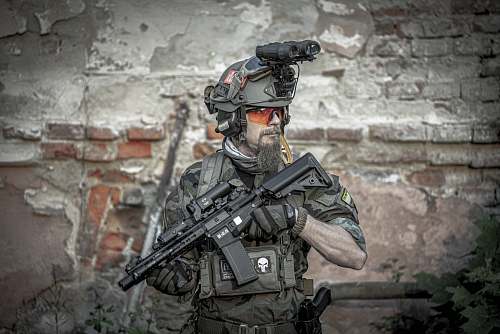 weaponry soldier man holding assault rifle while standing near building gun