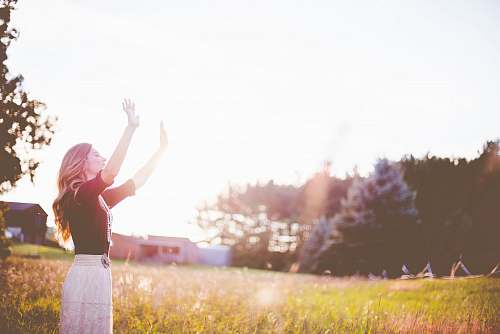 prayer woman hands up in front of green meadows grass