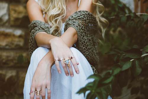 fashion woman sitting beside plant and concrete wall jewelry