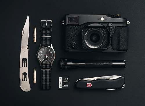 camera black camera, round silver-colored analog watch, black Swiss Gear pocketknife, and black flashlight electronics