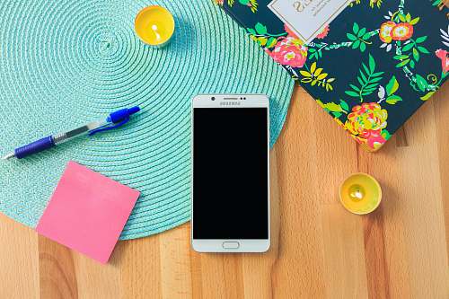 phone white Samsung Galaxy smartphone on top of blue place mat near blue click pen samsung