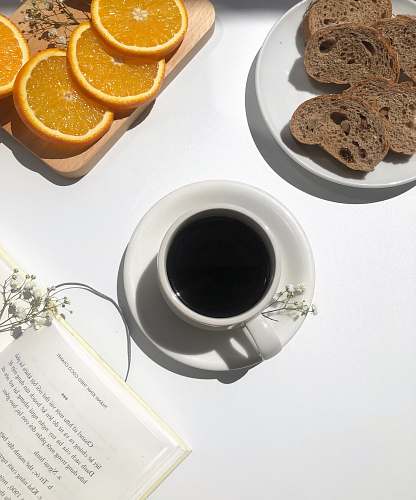 plant coffee in mug near breads and oranges coffee cup