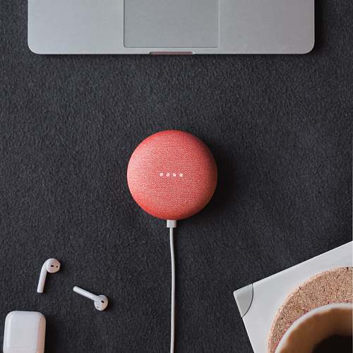 tech flat lay photography of coral Google Home Mini on black surface beside Apple AirPods cincinnati