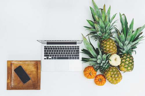 pineapple pineapple fruits near MacBook on white surface food