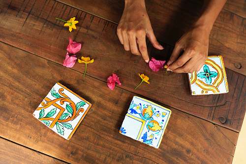gambling person holding pink flower petal on brown parquet floor game