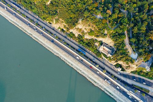 aerial photography of highway between body of water and mountain during daytime