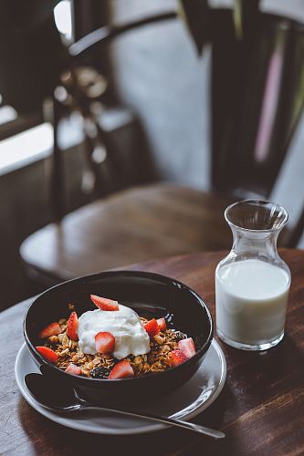 bowl of cereal with strawberries beside glass of milk on table