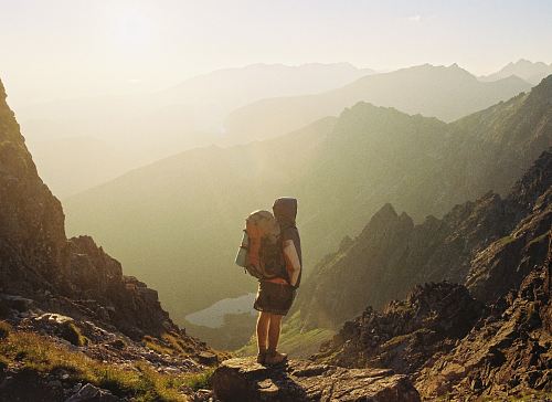 climber standing on rock near overlooking view of mountain at daytime