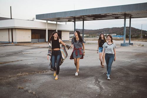 four girls walking near warehouse during daytime