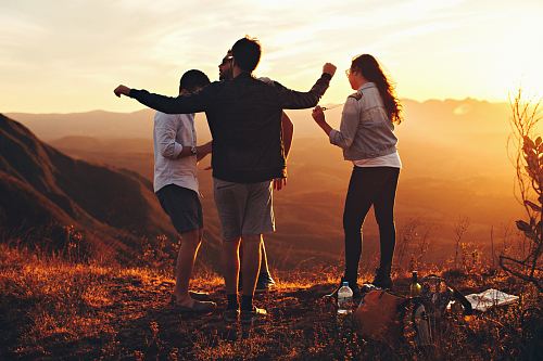 four people standing on edge of mountain