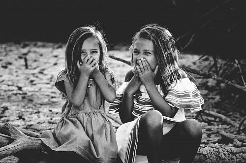 grayscale photography of two girls closing their mouths